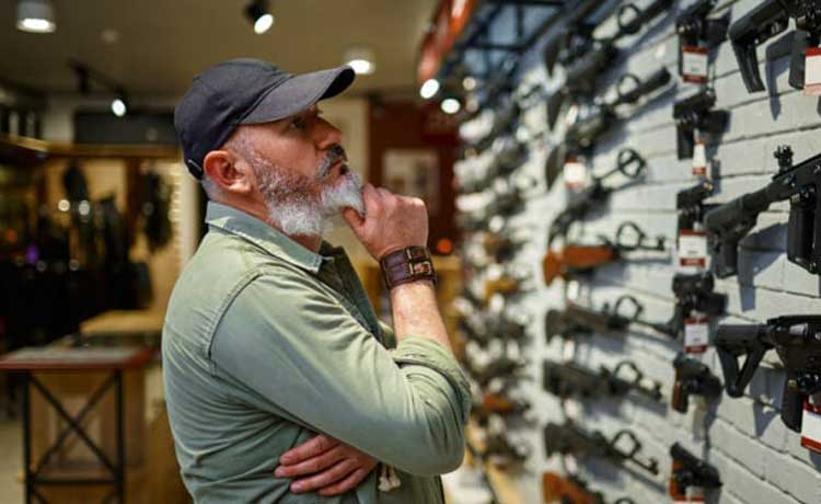 Un homme choisit une arme dans une armurerie.