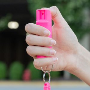 Une femme tient une bombe lacrymogène accrochée en porte-clé.