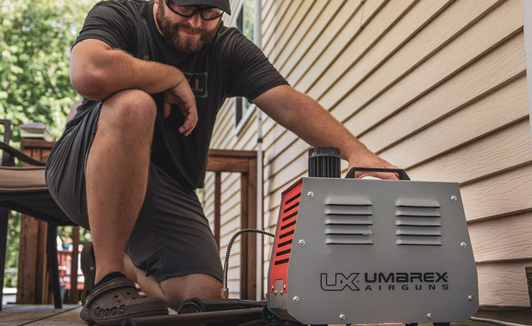 Un homme recharge son arme PCP avec son compresseur PCP.