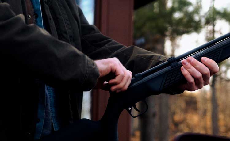 Un homme arme une carabine à plomb.