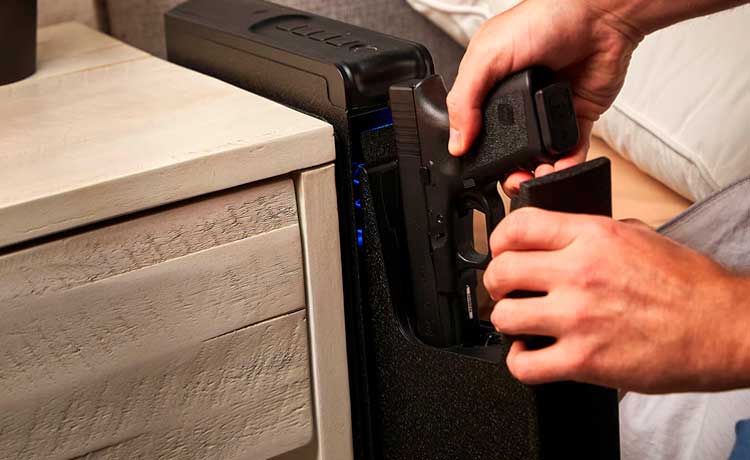 Coffre-fort pour arme de poing à proximité d'une table de chevet.