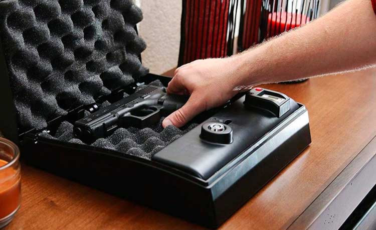 Une personne dépose son arme de poing dans un coffre-fort.