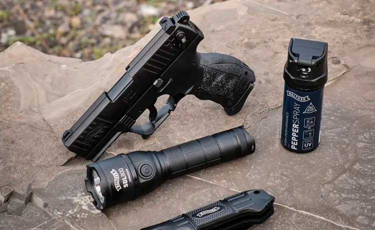 Pistolet d'alarme Walther posé sur un rocher avec des armes de défense