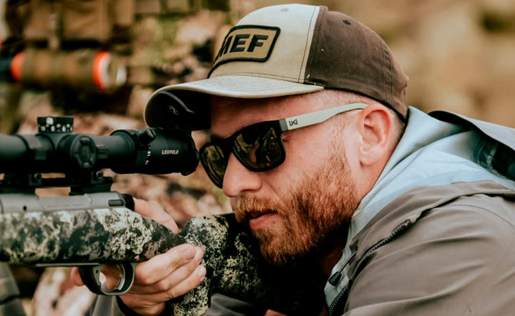 Un homme tient une arme longue et porte des lunettes de protection.